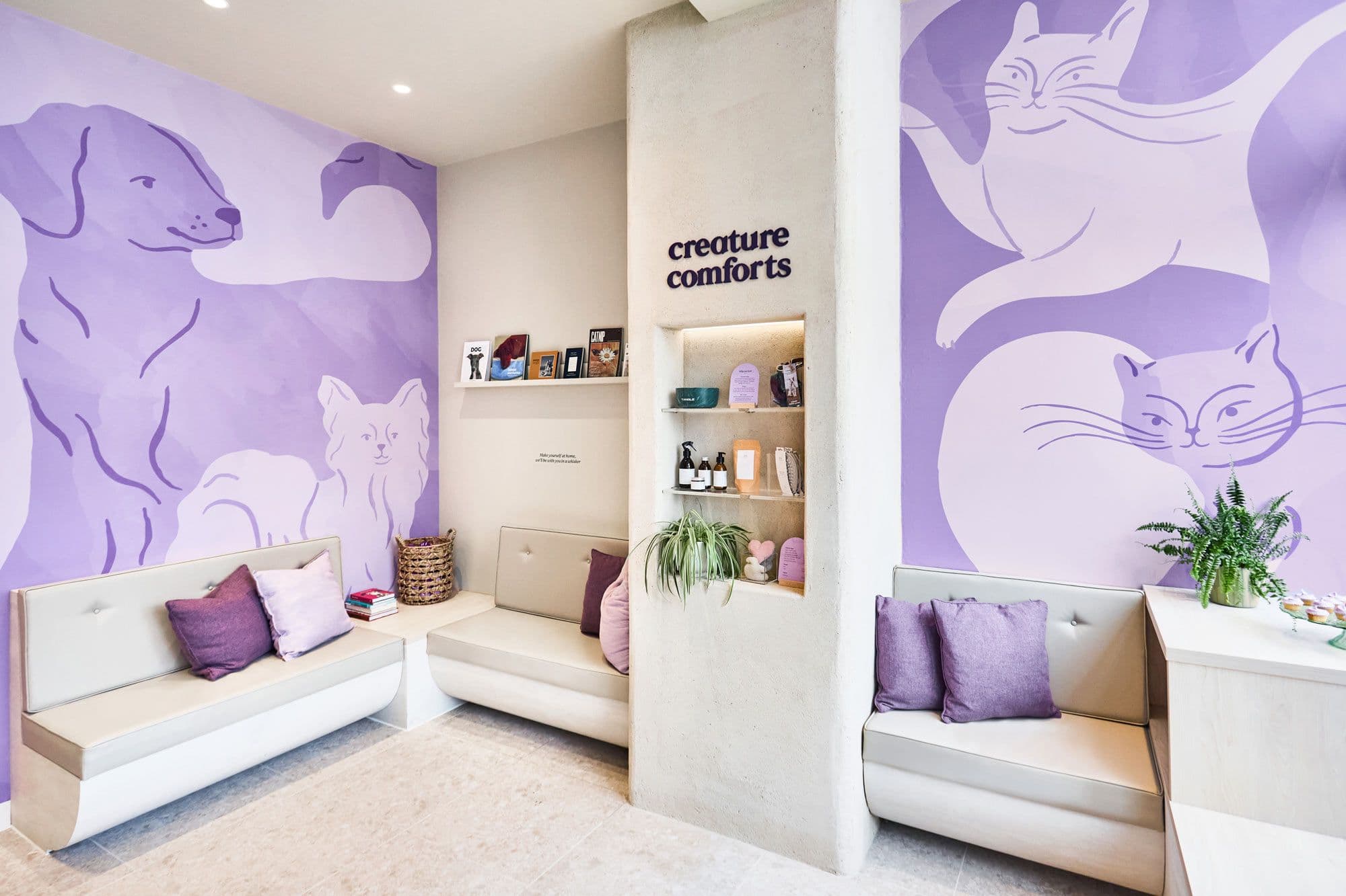 A bright interior view of Creature Comfort's Notting Hill clinic with welcoming sofas, pet toys and Creature Comforts branding on the wall. 